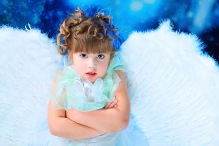 Beautiful little angel at a snowy background.の写真素材