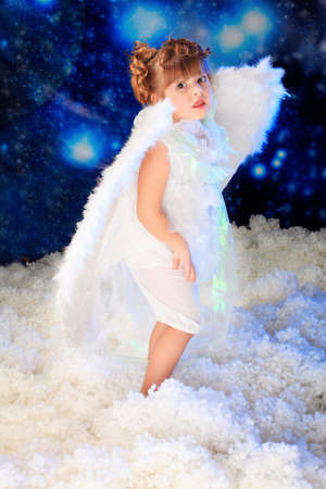 Beautiful little angel at a snowy background.の写真素材