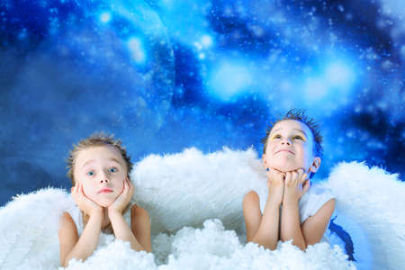 Beautiful little angels at a snowy background.の写真素材
