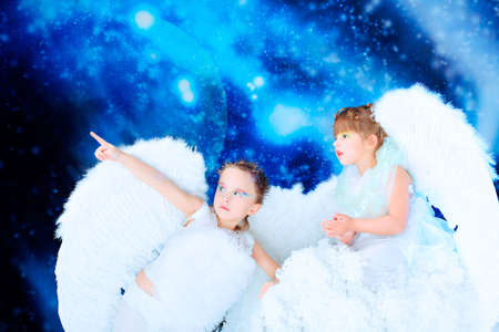 Beautiful little angels at a snowy background.の写真素材