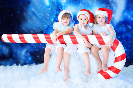 Beautiful little angelic children  with a huge candy at a christmas background.の写真素材