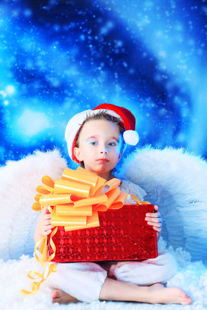 Beautiful little angelic child  with a present at a stellar sky.の写真素材