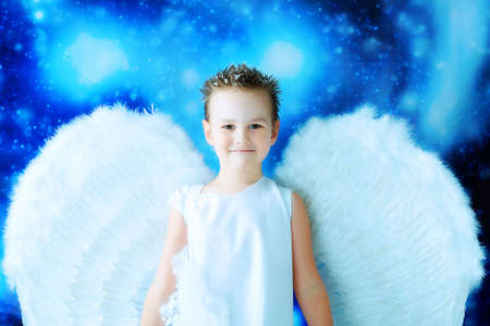 Beautiful little angel at a snowy background.の写真素材