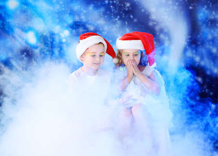 Beautiful little angelic children in a smoke at a stellar sky.の写真素材