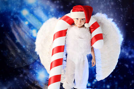Beautiful little angelic child  with a huge candy at a christmas background.の写真素材