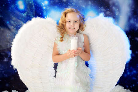 Beautiful little angel at a snowy background.の写真素材