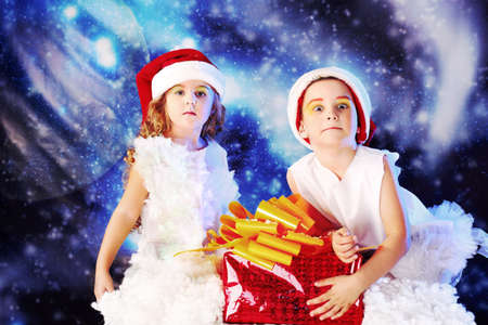 Beautiful little angelic children with a present at a stellar sky.の写真素材