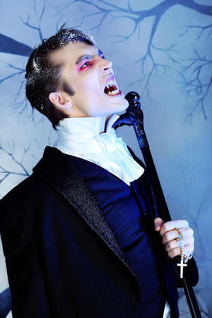 Portrait of a handsome young man with vampire style make-up. Shot in a studio.