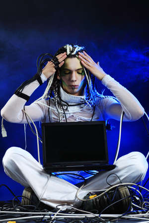 Shot of a futuristic young man sitting with a laptop and wires.の写真素材