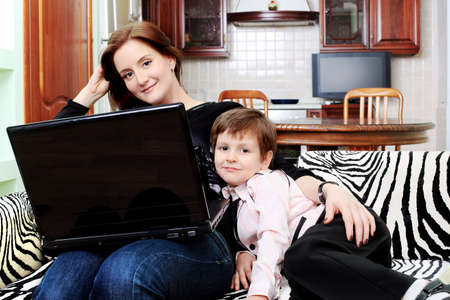 Happy woman with her son is looking at a laptop at home.の写真素材