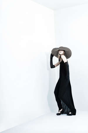 Portrait of a beautiful girl in elegant black dress and a  hat. の写真素材