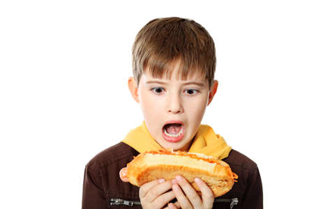 Shot of a hungry boy with a tasty hot dog. Isolated over white background.の写真素材