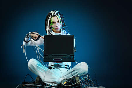 Shot of a futuristic young man sitting with a laptop and wires.の写真素材