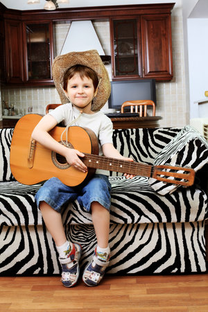 Shot of a little boy playing his guitar at home.
