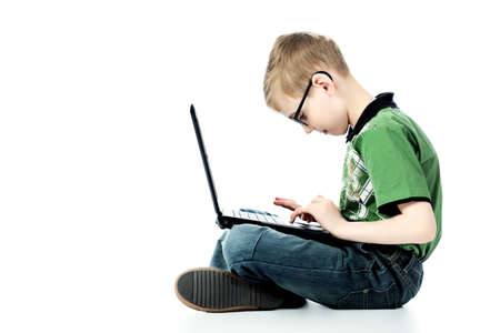 Shot of a boy sitting with his laptop. Isolated over white background.の写真素材