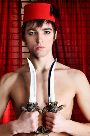 Shot of a man in oriental costume holding daggers.