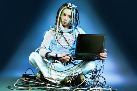 Shot of a futuristic young man sitting with a laptop and wires.