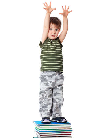 Portrait of a cute little boy standing on books. Isolated over white background.の写真素材