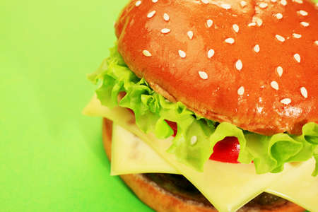 Appetizing cheeseburger over green background.の写真素材