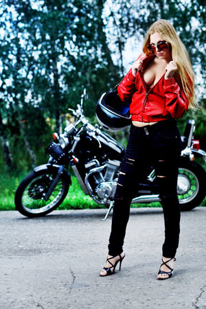 Shot of an attractive woman biker posing near her motorcycle.