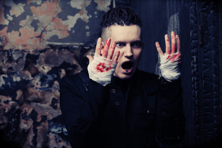 Shot of a scary man with bloody hands,  gothic style. Halloween, horror.