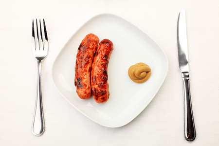 Appetizing grilled sausages with mustard on a plate.の写真素材