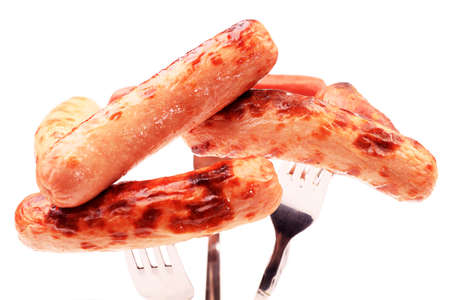 Close-up of fried sausages  on forks. Isolated over white background.の写真素材