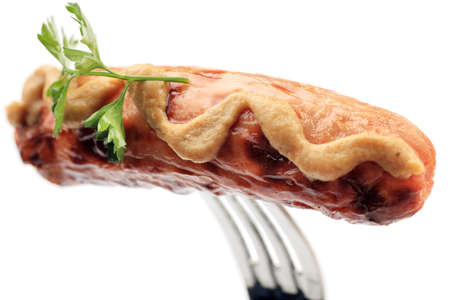 Close-up of fried sausage with mustard on a fork. Isolated over white background.の写真素材