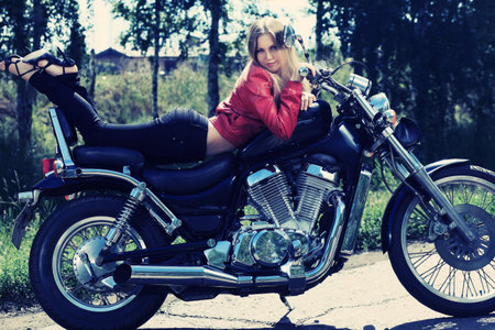 Shot of an attractive woman biker posing on her motorcycle.