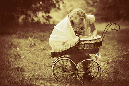 Shot of a cute girl walking with baby buggy at summer park.の写真素材