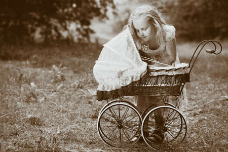 Shot of a cute girl walking with baby buggy at summer park.の写真素材