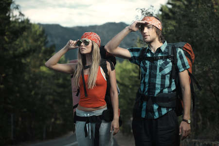 Two young people tourists hitchhiking along a road.の写真素材