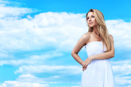 Beautiful young woman posing over summer sky.の写真素材