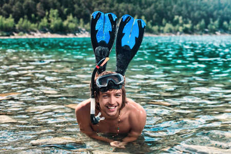 Happy young man with snorkelling gear on a sea beach.の写真素材
