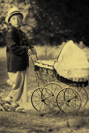 Shot of a cute boy in a suit walking with baby buggy at summer park.