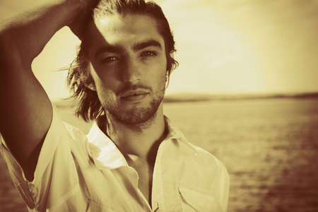 Handsome young man posing over sea and blue sky.の写真素材