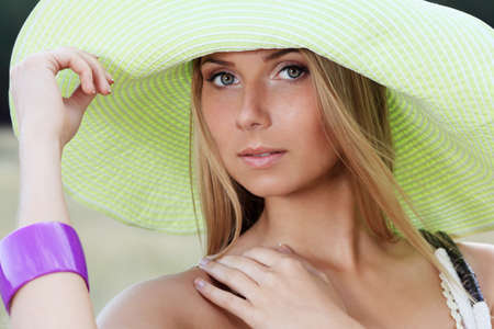 Beautiful young woman in elegant hat posing outdoor.の写真素材