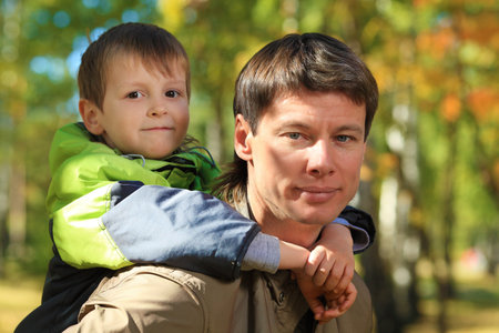 Happy father walking at the autumn park with his son.