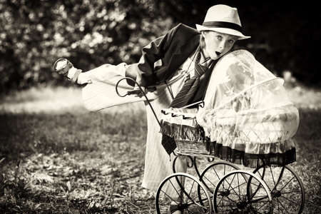 Shot of a cute boy in a suit walking with baby buggy at summer park.の写真素材