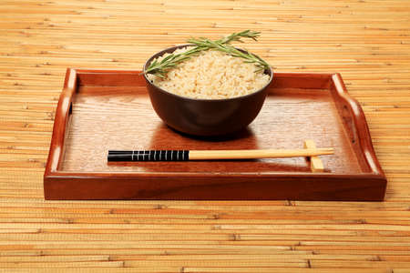 Steamed long rice in a brown bowl with chopsticks.の写真素材