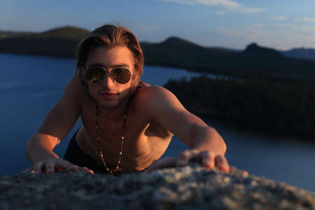 Handsome young man posing over sea and mountains.の写真素材