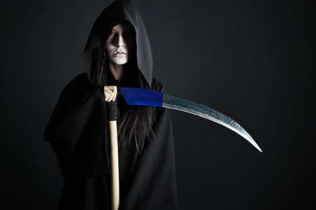 Woman death reaper over black background. Halloween.の写真素材