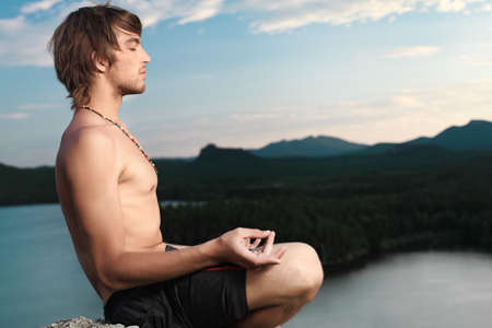 Handsome young man doing yoga exercise outdoors.の写真素材