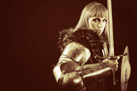 Portrait of a medieval female knight in armour over black background.の写真素材