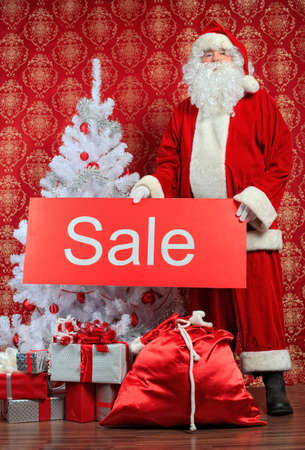 Santa Claus with presents and New Year tree at home. Christmas sale.の写真素材