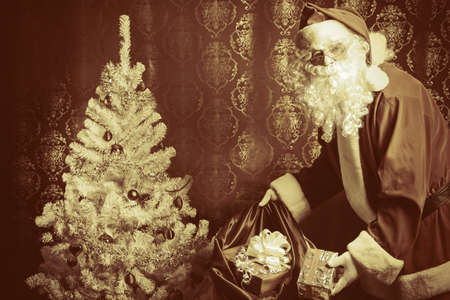 Santa Claus with presents and New Year tree at home. Christmas.の写真素材