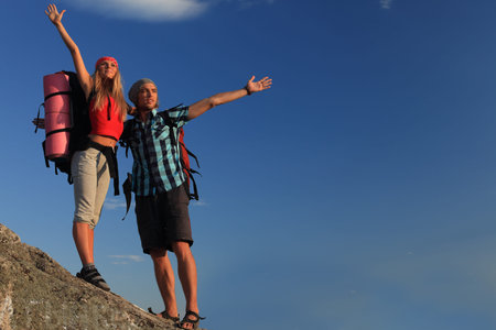 Couple of tourists are standing at the top of a mountain with a feeling of freedom.の写真素材