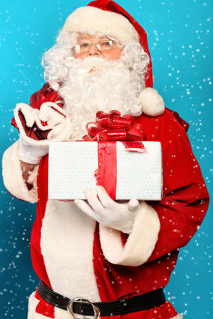 Portrait of Santa Claus with present over blue background. Christmas.の写真素材
