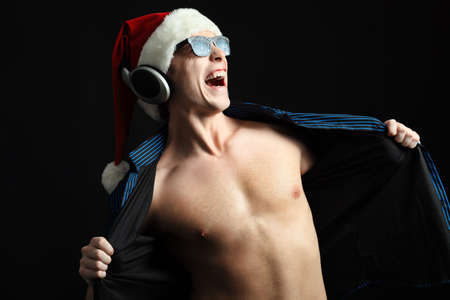 Portrait of a funny young man in Santa Claus hat and headphones. Christmas.の写真素材