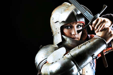 Portrait of a medieval female knight in armour over black background.の写真素材